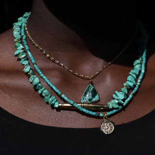 a stack of green and gold necklaces over velvet