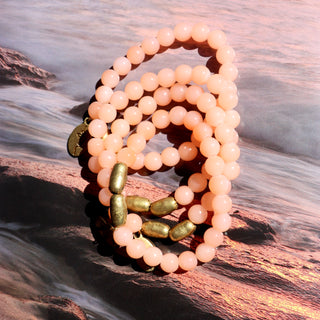 bright peach color glass beads with accent brass beads and a brass Often Wander charm.