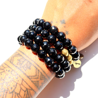 Faceted shiny black beads with brass accent beads along with an Often Wander charm.