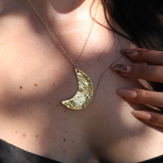 Hammered Crescent Moon Necklace on 14karat gold fill chain. On a white background. The necklace is shiny gold.