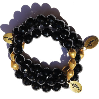 Faceted shiny black beads with brass accent beads along with an Often Wander charm.