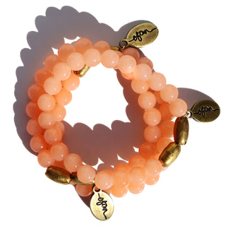 bright peach color glass beads with accent brass beads and a brass Often Wander charm.