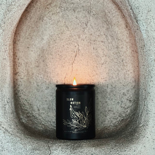 a lit candle in a black jar in a concrete alcove