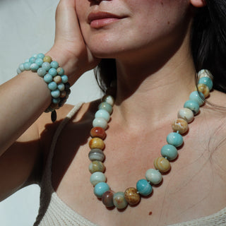 Woman wearing a colorful beaded necklace and bracelet against a white background