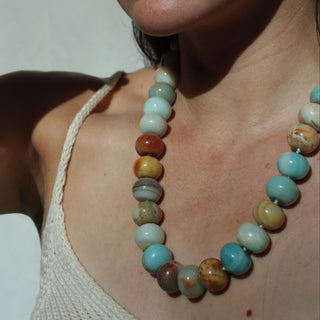 Woman wearing a beaded necklace and bracelet against a neutral background