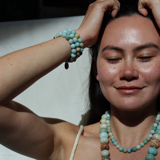 Woman wearing a necklace and bracelets against a plain background