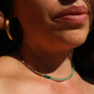 Asymmetrical design with aventurine on one side and shiny gold beads on the other with a malachite accent in the middle.