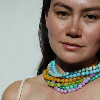 Woman wearing a colorful beaded necklace against a plain background
