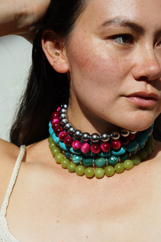 Close-up of a woman wearing a colorful beaded necklace against a neutral background