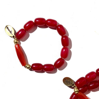 A red beaded bracelet with a gold-toned oval charm engraved with 'Sauder', displayed on a clean white background.