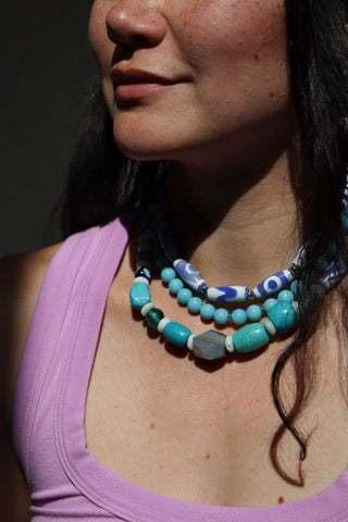 Close-up of a person wearing a colorful beaded necklace with a blurred background