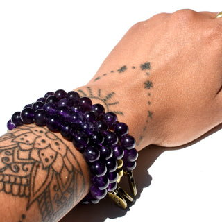 Deep purple shiny and translucent beads with brass accent beads and an Often Wander charm.