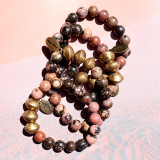 pink with black marbled like texture. Along with 3 brass accent beads and a Often Wander charm.