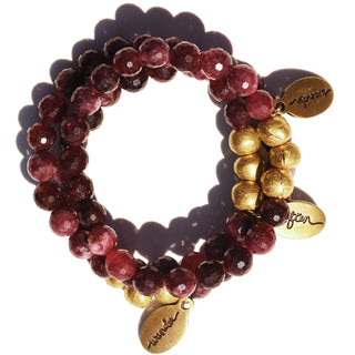 Beautiful faceted round ruby colored jade beads strung together on a beaded bracelet with brass accents and an often wander charm.