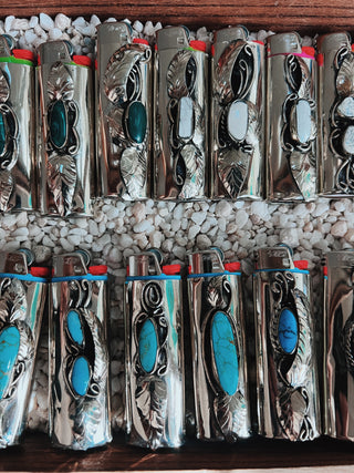 Collection of silver lighters with turquoise stones on a wooden surface.