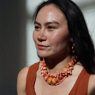 Woman wearing a coral necklace against a plain background