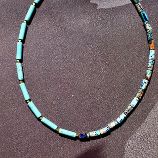asymmetric necklace with Turquoise tube beads on one side & Turquoise mixed with lapis lazuli tube beads on the other side along with a gold bead in the middle.
