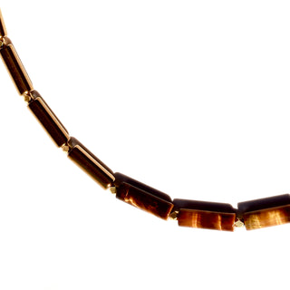 Asymmetrical design with Tiger's Eye tube beads on one side, shiny gold tube beads on the other side and a Often Wander charm on the back of the necklace