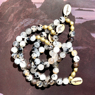 a beautiful combination of clear quartz and black tourmaline beads, brass accent beads and an Often Wander charm.