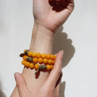 Hand wearing a bracelet with yellow beads on a white background