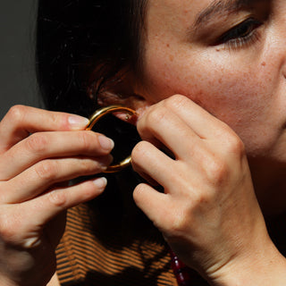 Person adjusting an earring in front of a mirror