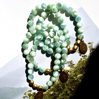 pale mint blue beads with hints of green, a few brass accent beads and a brass Often Wander charm.