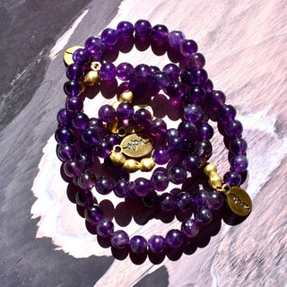 Deep purple shiny and translucent beads with brass accent beads and an Often Wander charm.