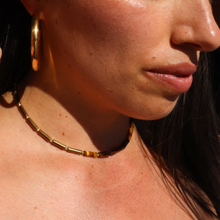 Asymmetrical design with Tiger's Eye tube beads on one side, shiny gold tube beads on the other side and a Often Wander charm on the back of the necklace