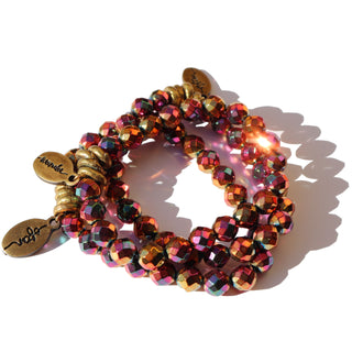 shiny metallic faceted rainbow beads with colors of magenta, pink, purple, orange and gold with brass accent beads and a small Often Wander charm.