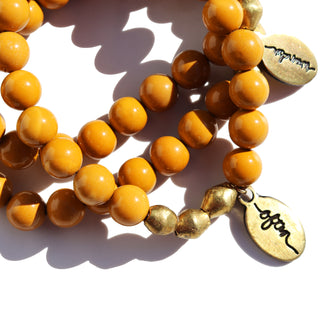 Dark yellow beads with a few brass accent beads along with an Often Wander charm.